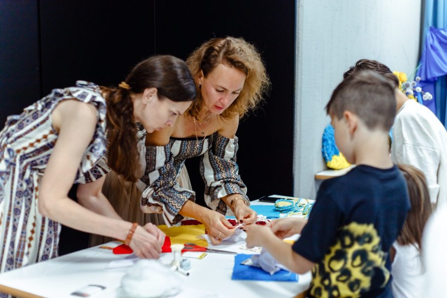Zur Seite Bildungsangebote Zwei Erwachsene und ein Kind basteln gemeinsam an einem Tisch. Materialien liegen bereit.