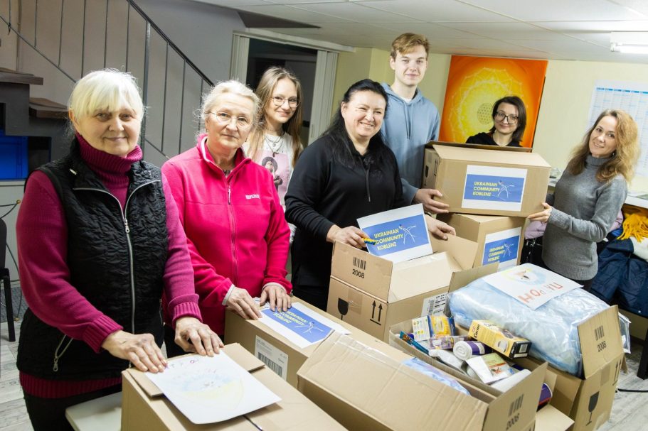 Zur Seite Spenden Gruppe von Menschen, die Pakete in einem Raum mit Kisten und Materialien organisieren.