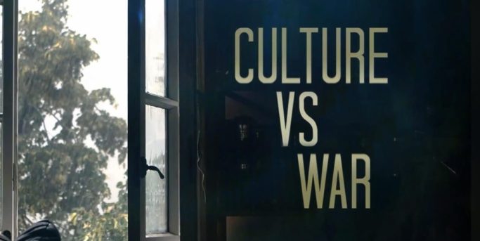 Titel "Kultur vs. Krieg" steht vor einem Fenster und Pflanzen im Hintergrund.