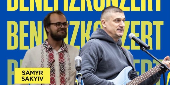 (c) Marianna Karabut Zwei Männer auf einer Bühne, einer singt, der andere lächelt im Hintergrund.